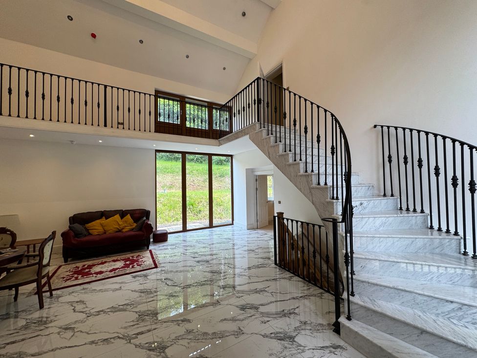 An entryway with a staircase and sofa at Plas Glyndwr in Crickhowell