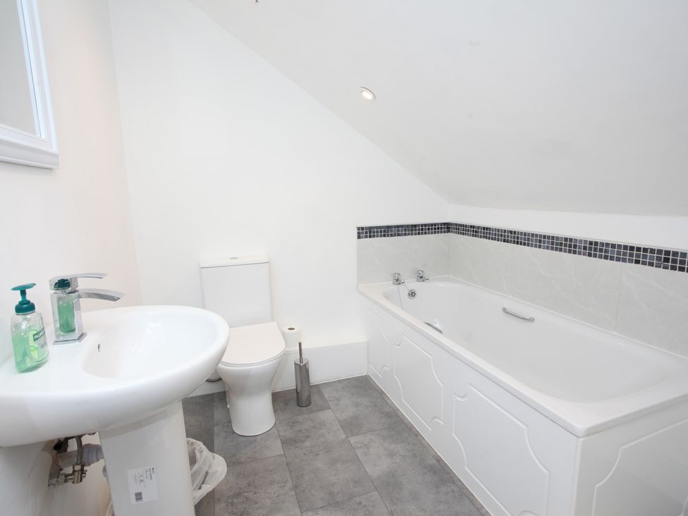 A bathroom with a bathtub, toilet, and sink at Plas Glyndwr in Crickhowell