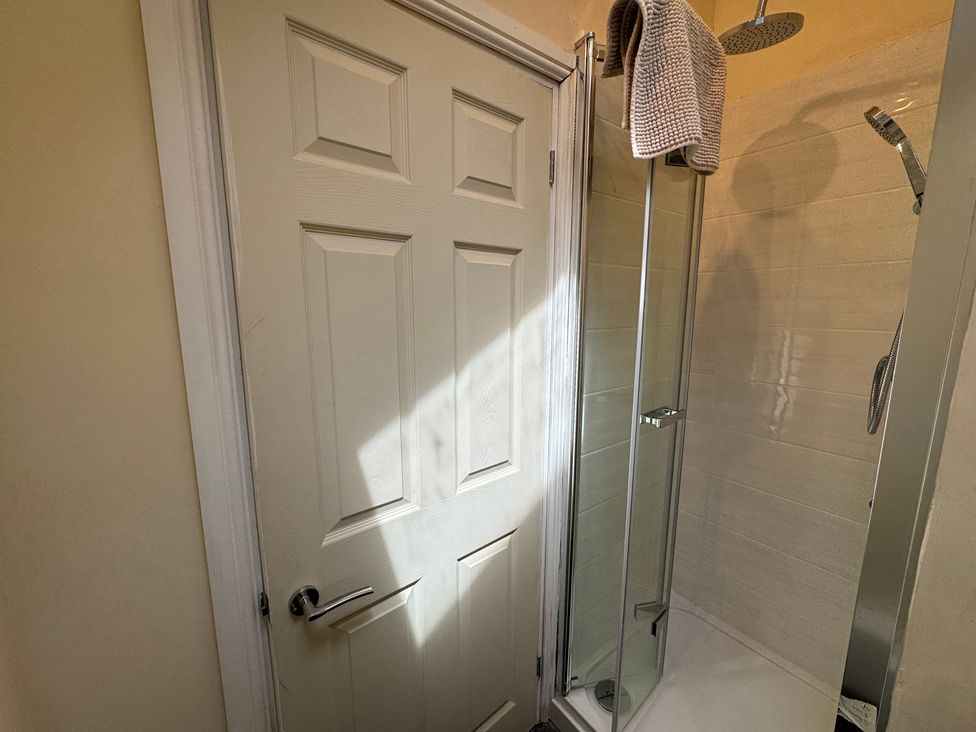 A shower with a door and a towel hanging at Plas Glyndwr in Crickhowell
