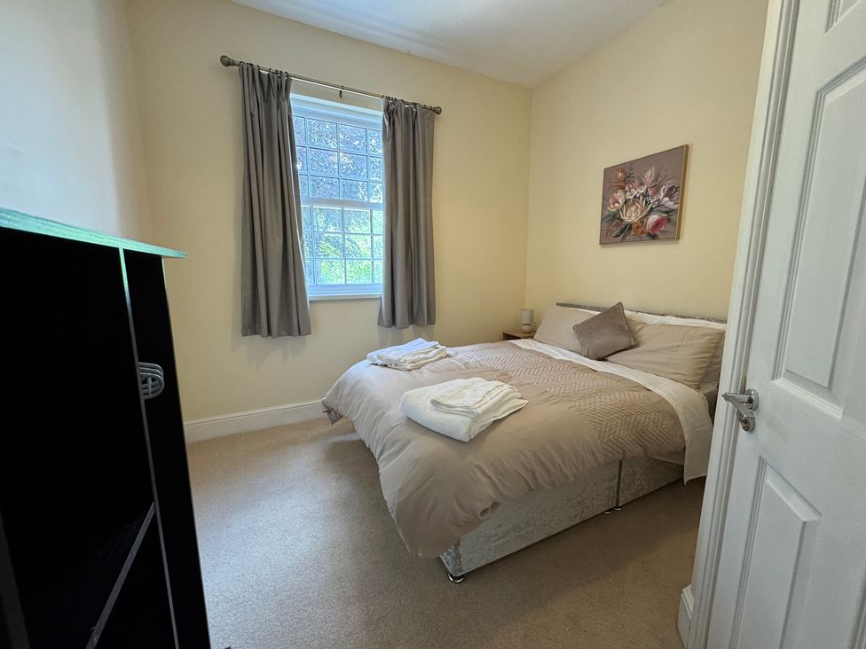 A bedroom with a bed, window, and bedside table at Plas Glyndwr in Crickhowell