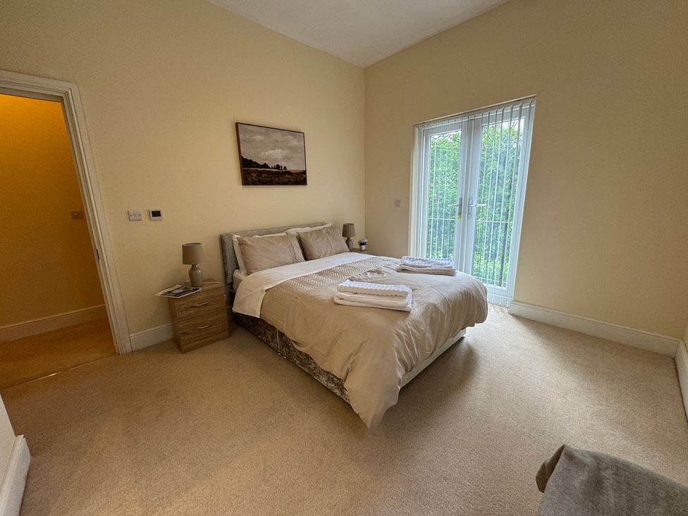 A bedroom with a bed and sliding door at Plas Glyndwr in Crickhowell