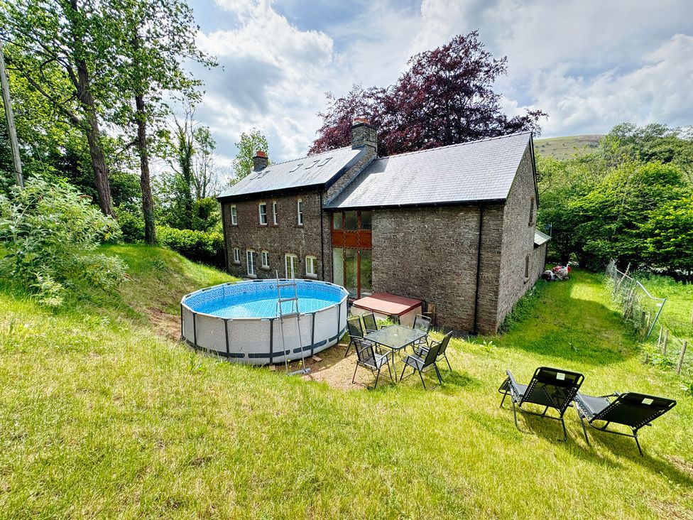 An outdoor garden with a pool and seating area at Plas Glyndwr in Crickhowell