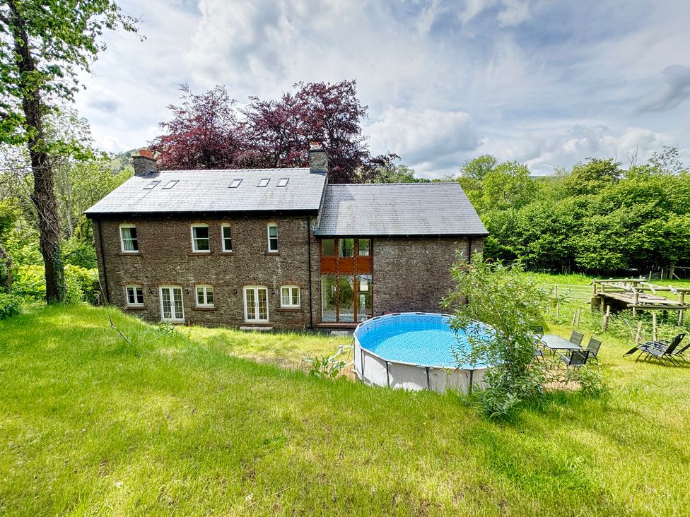 A house with a pool and grass area at Plas Glyndwr in Crickhowell
