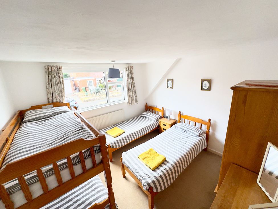 A bedroom with two single beds and a bunk bed at 38 Dale End Brancaster Staithe near Burnham Market