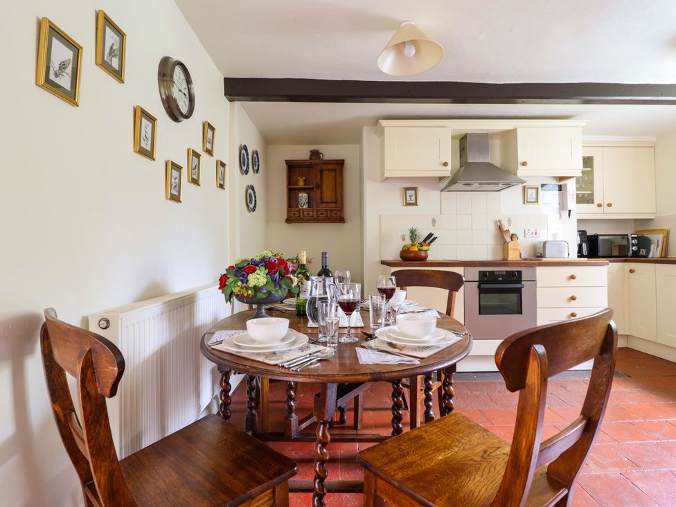 A kitchen with a round dining table set for a meal at Penymaes in Bronygarth near Chirk