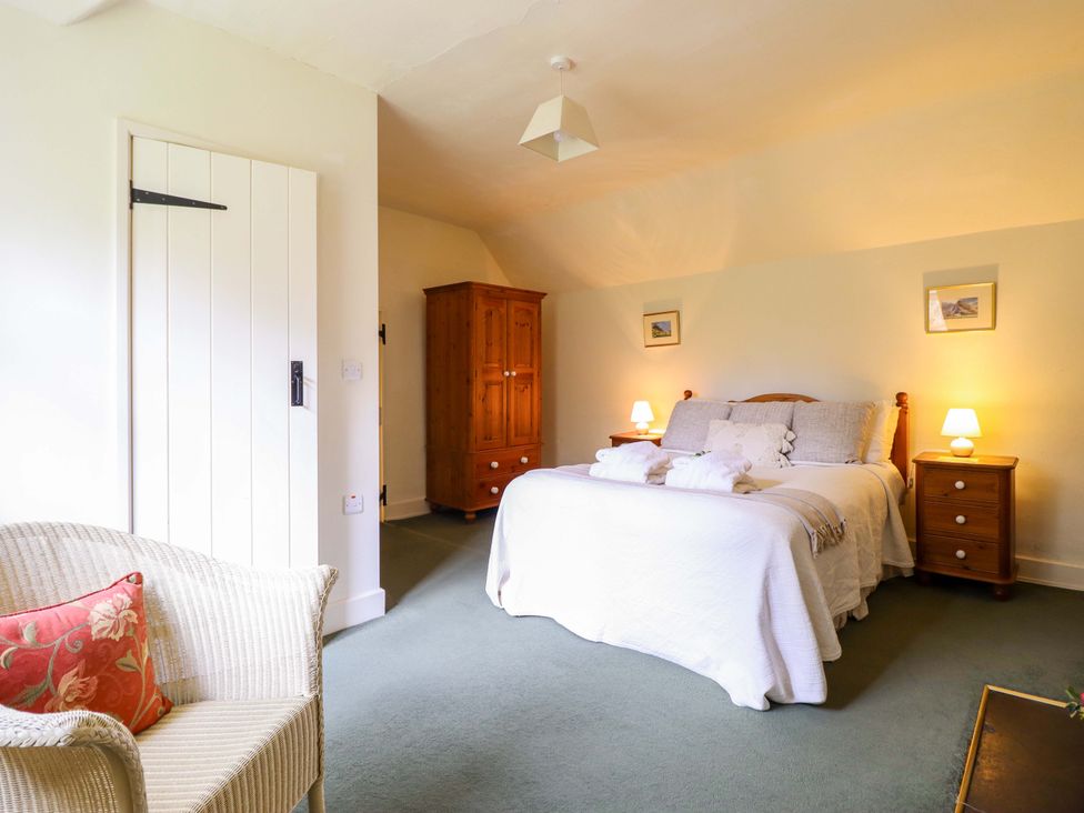 A bedroom with a bed nightstand and wardrobe at Penymaes in Bronygarth near Chirk