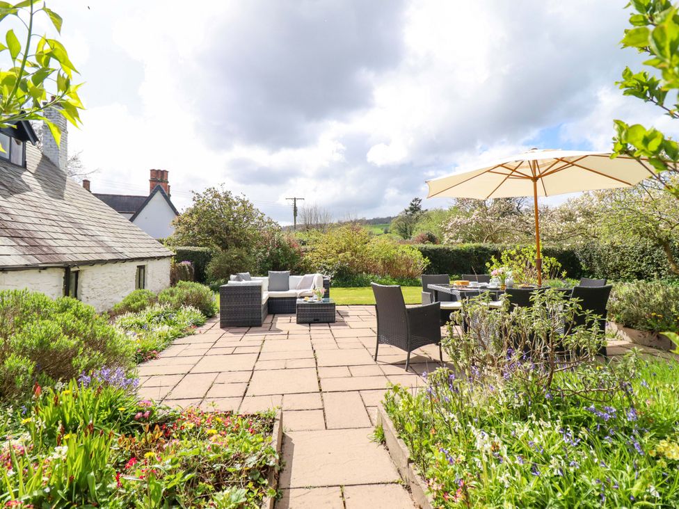 A garden with patio seating and an umbrella at Penymaes Bronygarth near Chirk