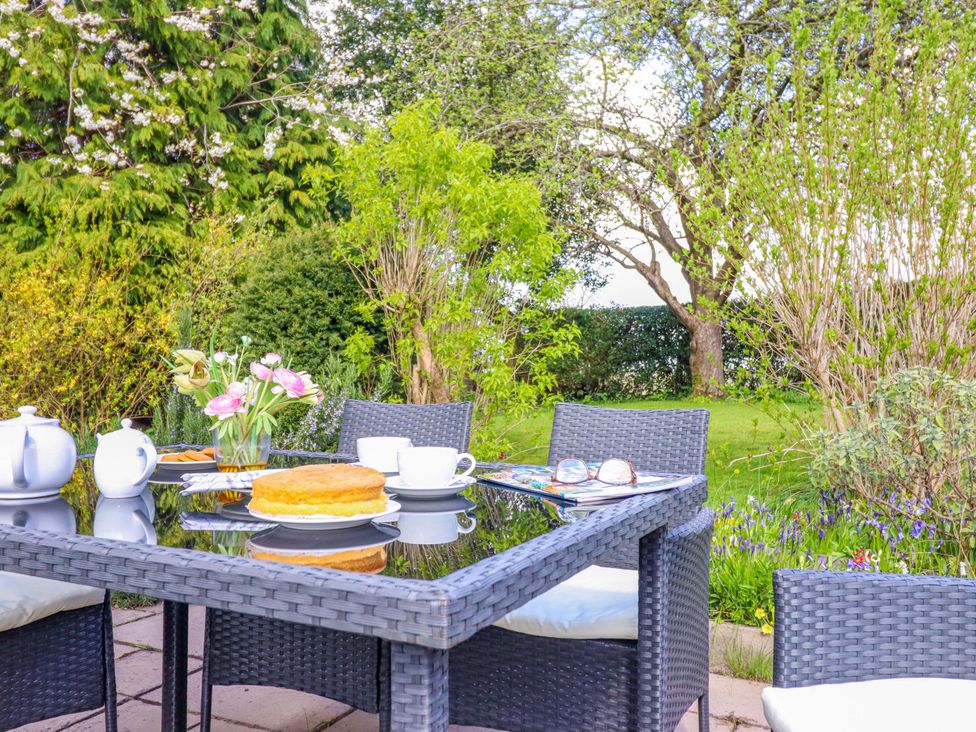 A garden with a table, chairs, teapot, cake, flowers and magazines at Penymaes in Bronygarth near Chirk