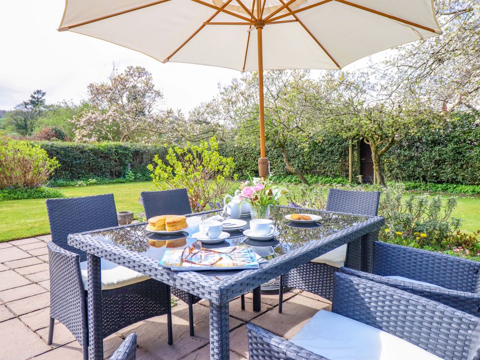 A garden with a table and chairs under an umbrella at Penymaes Bronygarth near Chirk