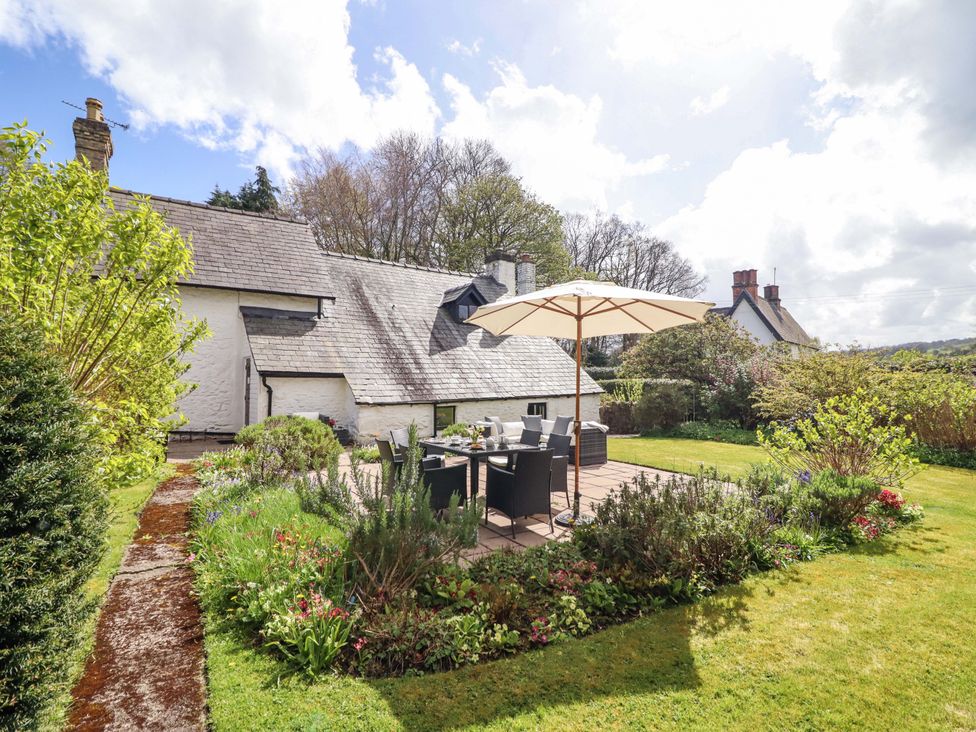 A garden with a table and chairs under a parasol at Penymaes Bronygarth near Chirk