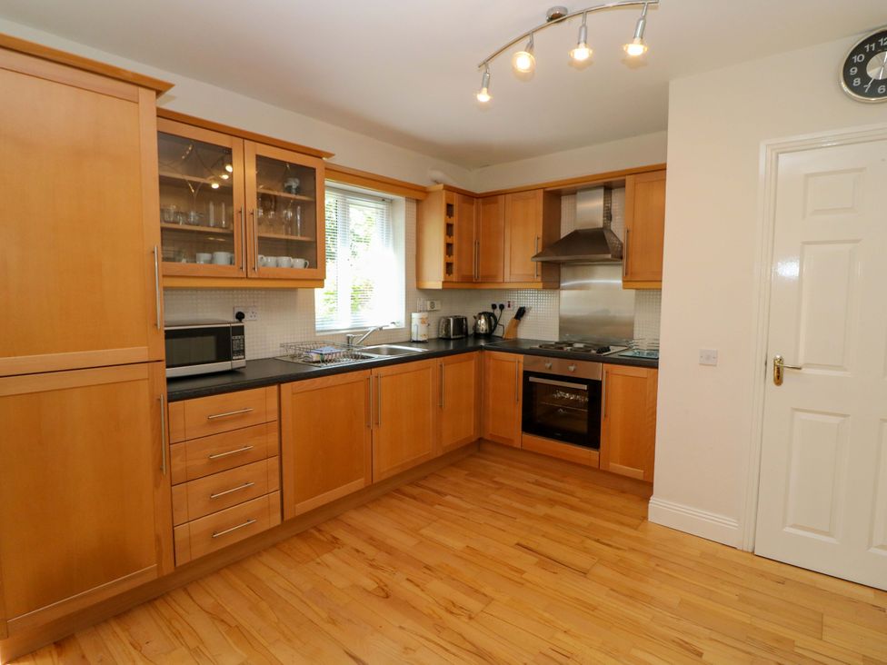 A kitchen with wooden cabinets and appliances at No. 4 Lansdowne Village Kenmare, The Ring of Kerry, County Kerry