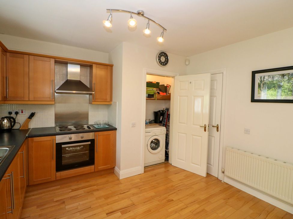 A kitchen with cabinets, a cooker, and a washing machine at No. 4 Lansdowne Village, Kenmare, The Ring of Kerry, County Kerry