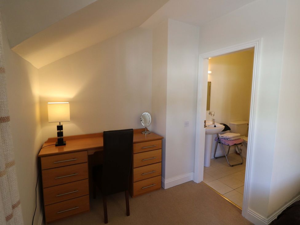 A bedroom with a desk and a door leading to a bathroom at No. 4 Lansdowne Village, Kenmare, The Ring of Kerry, County Kerry