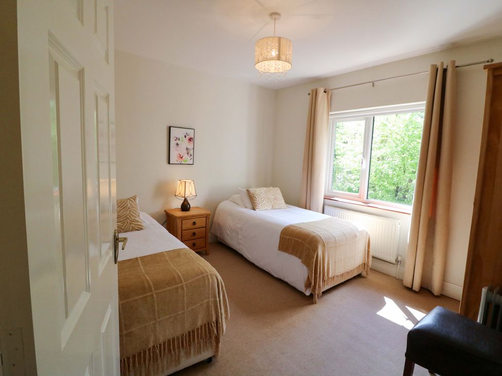 A bedroom with two beds and a lamp on a nightstand at No. 4 Lansdowne Village, Kenmare, The Ring of Kerry, County Kerry