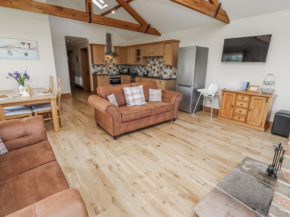 A living room with a sofa and dining table at Grey Croft Embleton