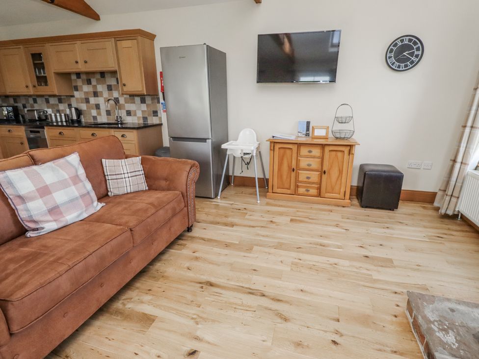 A living room with a sofa, television, and high chair at Grey Croft in Embleton