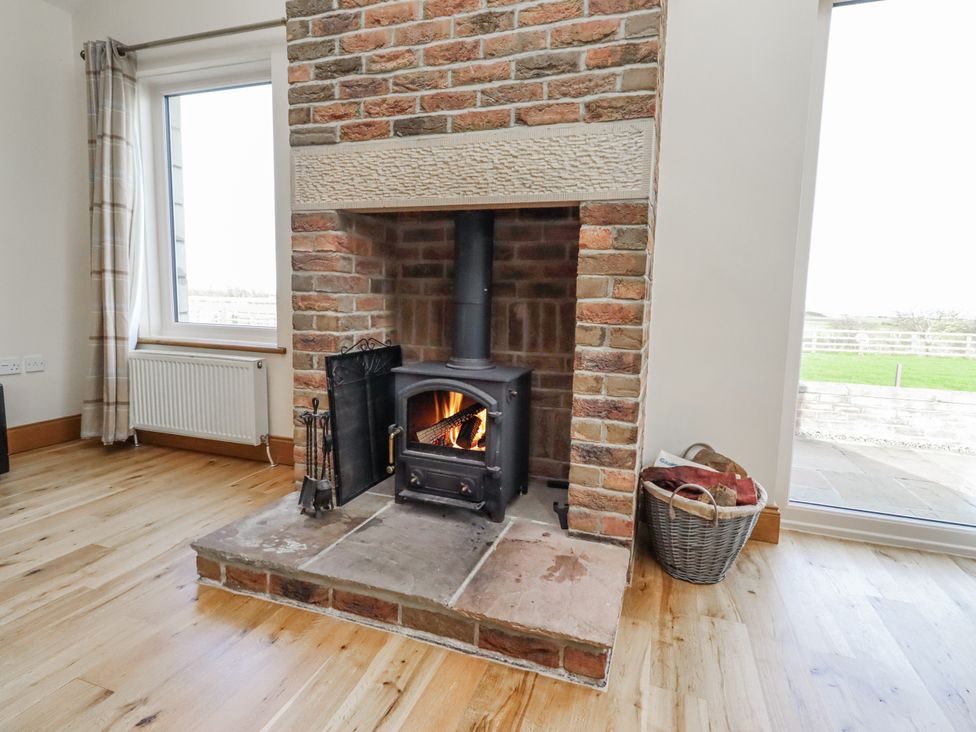 A living room with a fireplace and wood stove at Grey Croft in Embleton