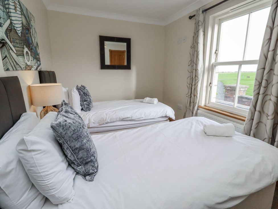 A bedroom with two beds and a window at Grey Croft in Embleton