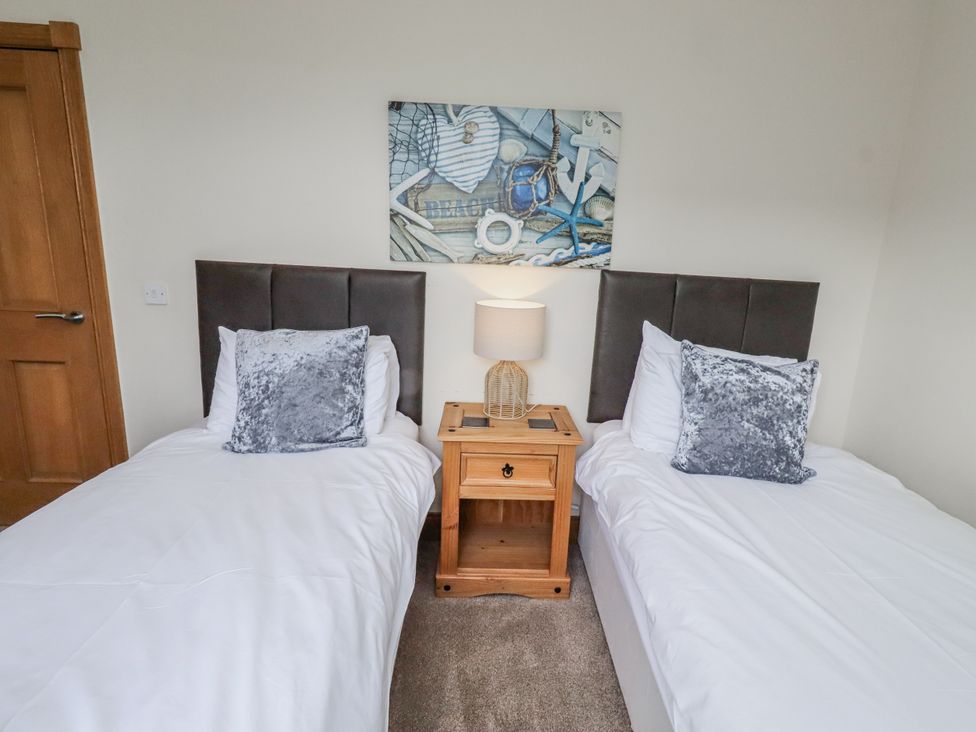 A bedroom with two single beds and a bedside table with a lamp at Grey Croft in Embleton