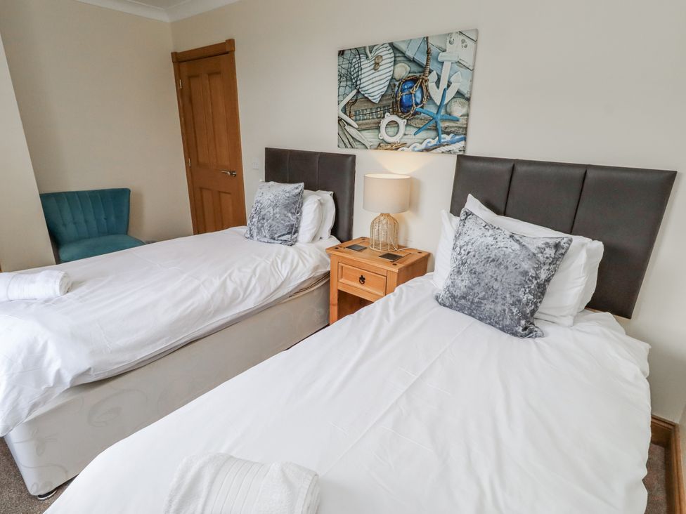 A bedroom with twin beds and a nightstand with a lamp at Grey Croft in Embleton