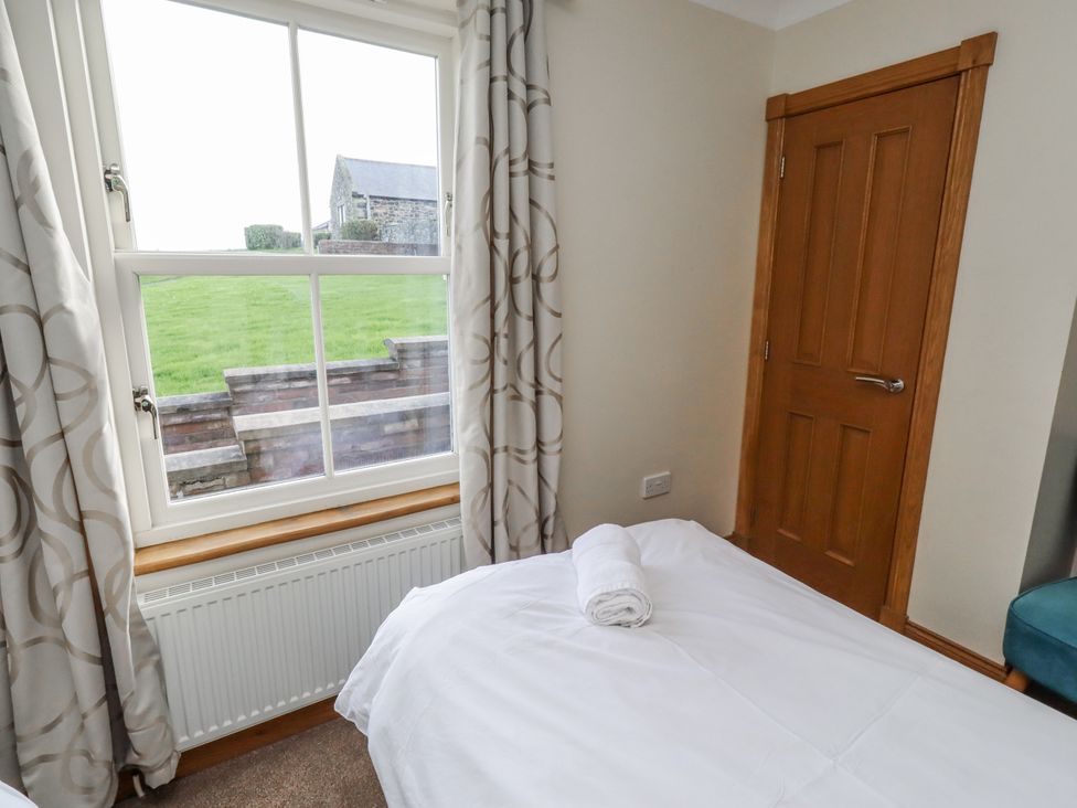 A bedroom with a bed and window at Grey Croft in Embleton