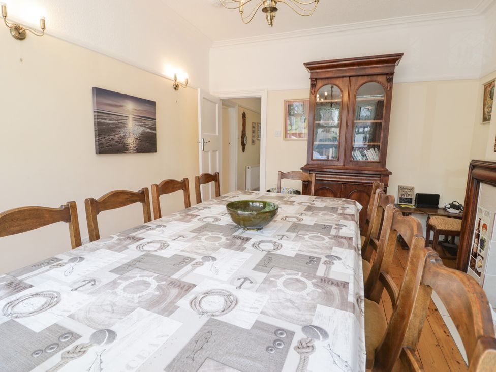 A dining room with a large table and wooden chairs at Meadway House in Rhos-on-Sea