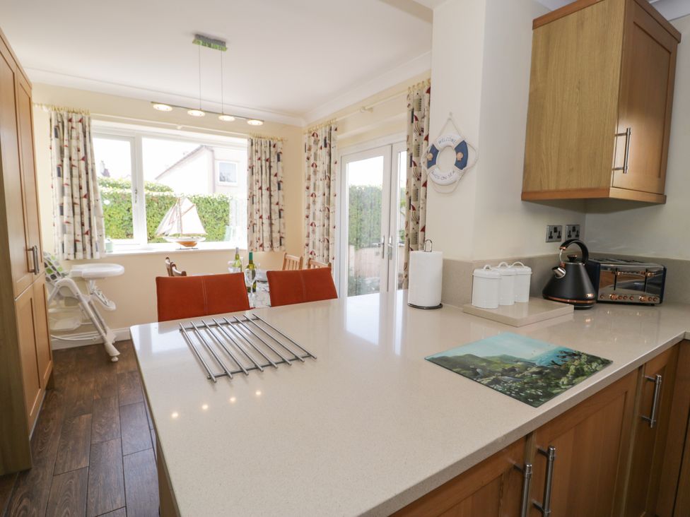 A kitchen with countertop, cabinets, kettle, toaster, and window at Meadway House Rhos-on-Sea