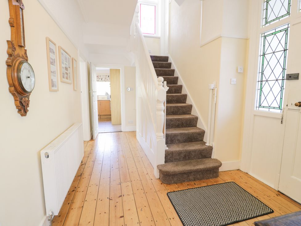 A hallway with a staircase and wall clock at Meadway House in Rhos-on-Sea
