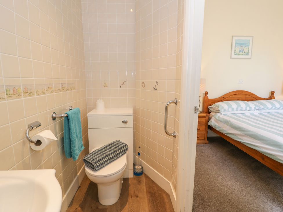 A bathroom with a toilet and sink, with a bedroom visible in the background at Meadway House in Rhos-on-Sea