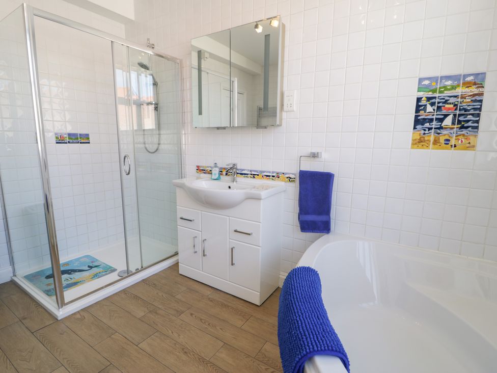 A bathroom with a shower, bathtub, vanity and mirror at Meadway House, Rhos-on-Sea