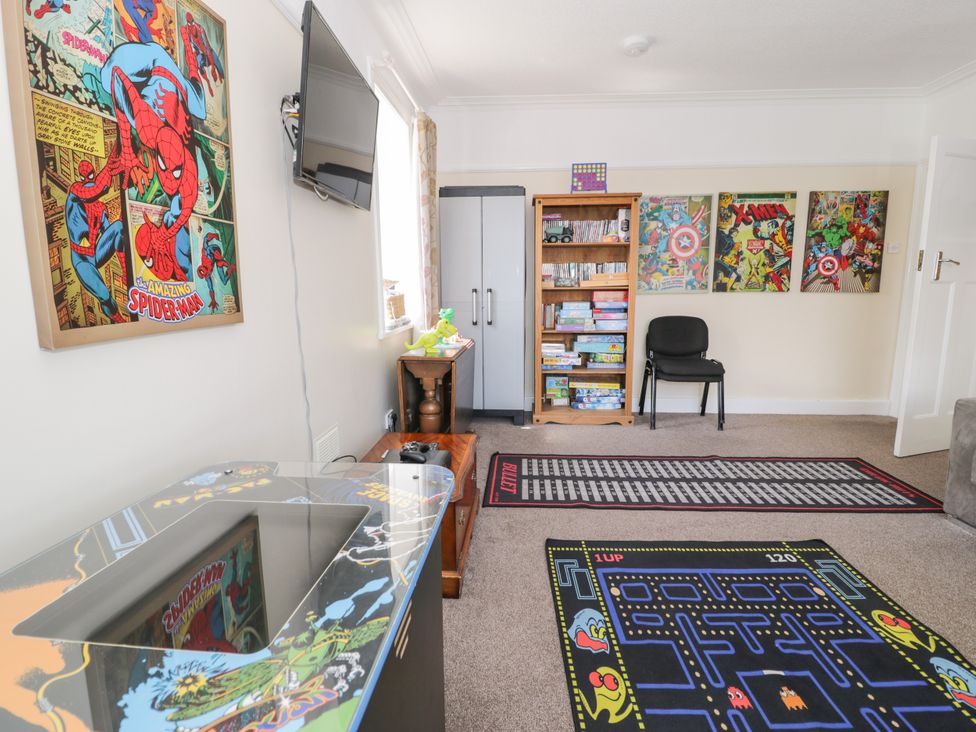 A snug with a Spider-Man poster, bookshelf, and gaming carpet at Meadway House Rhos-on-Sea