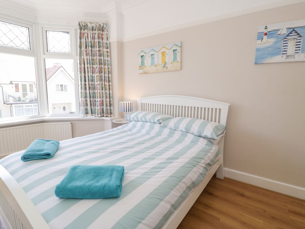 A bedroom with striped bed linen and a window at Meadway House in Rhos-on-Sea