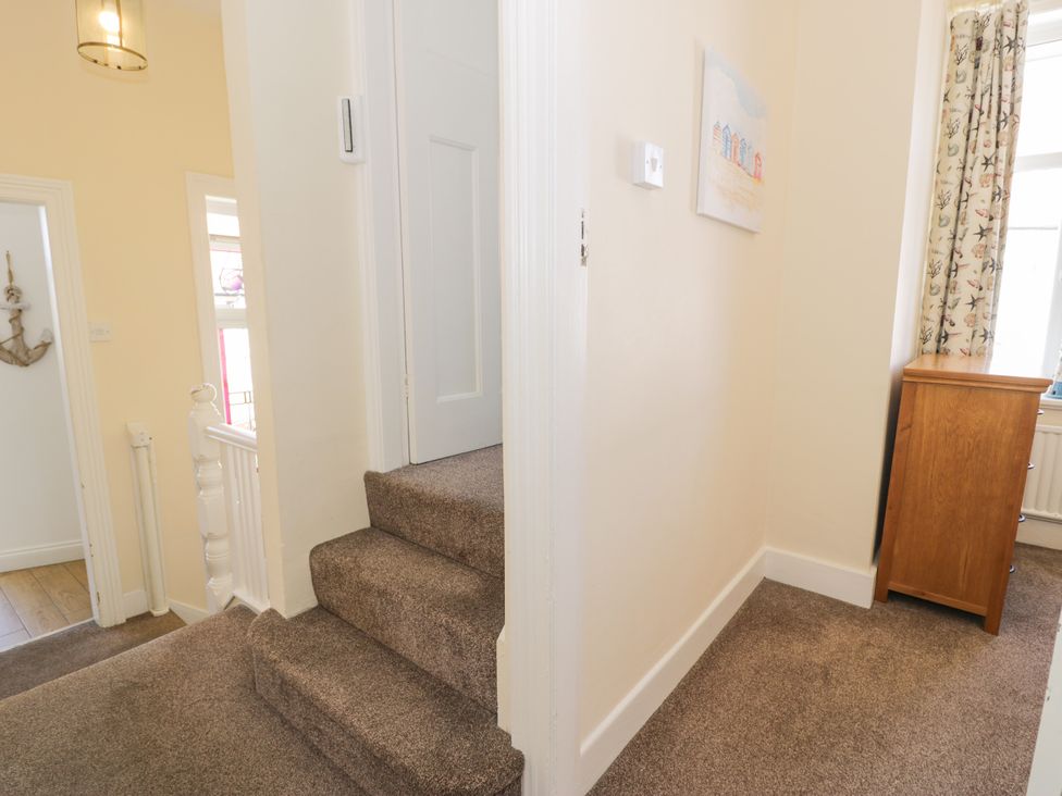 A hallway with a staircase and chest of drawers at Meadway House in Rhos-on-Sea