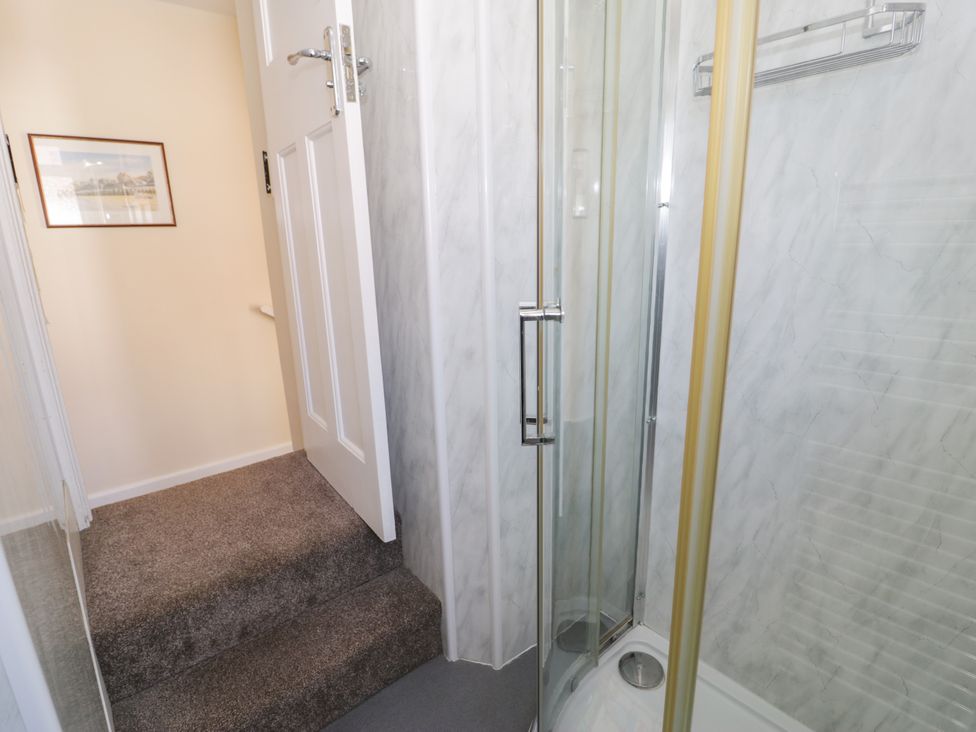 A bathroom with a shower and stairs at Meadway House Rhos-on-Sea