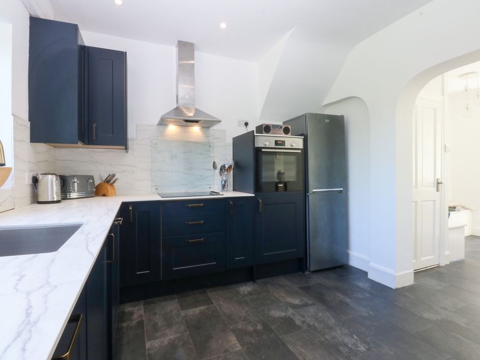 A kitchen with appliances and cabinetry at Monarfon in Benllech near Red Wharf Bay