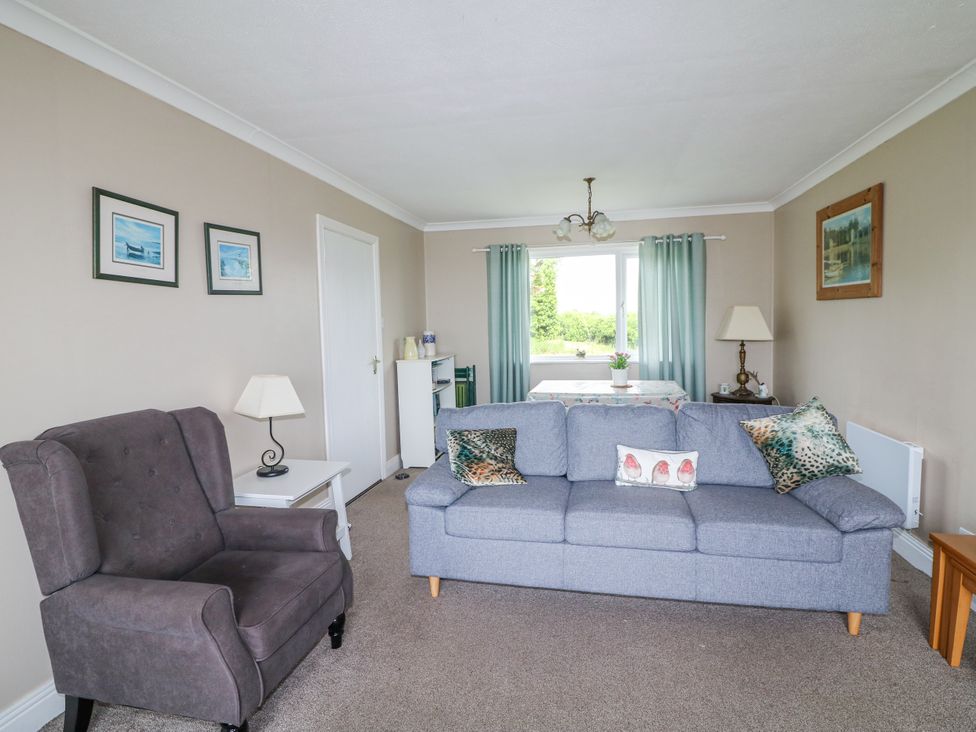 A living room with an armchair and a grey sofa at Findale Carne near Rosslare, County Wexford