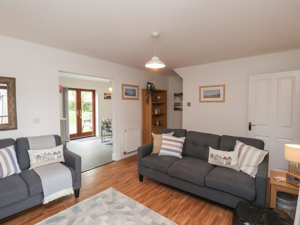 A living room with two grey sofas wooden floor and a doorway leading to a dining area at Buffers in Whitby