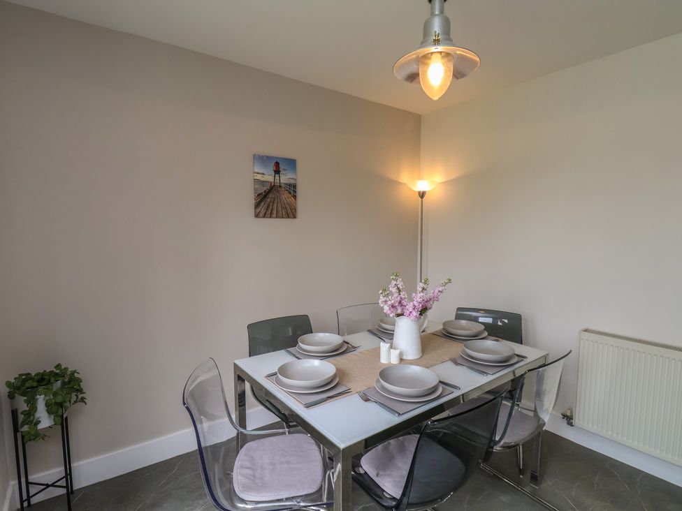 A dining room with a glass table set for six with plates and flowers at Buffers in Whitby