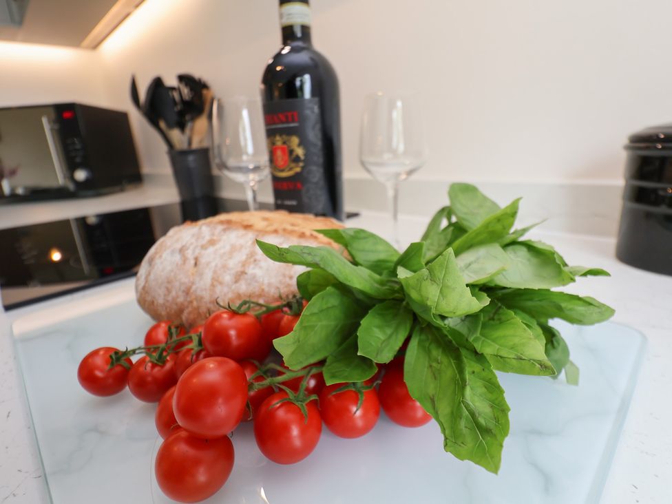 A kitchen counter with tomatoes on the vine basil leaves bread a bottle of wine and two wine glasses at Buffers in Whitby