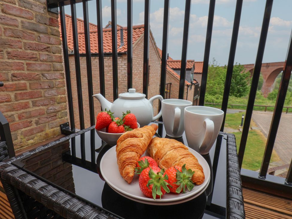 A balcony with a table holding croissants strawberries a teapot and two cups at Buffers in Whitby