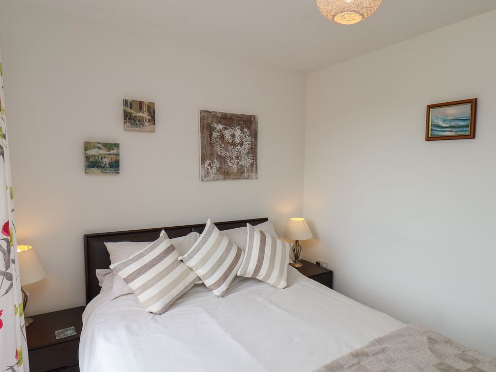 A bedroom with a bed three striped pillows bedside tables lamps and paintings on the wall at Buffers in Whitby