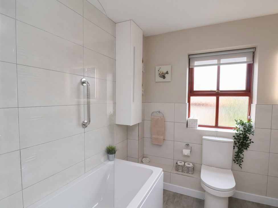 A bathroom with a white bathtub a toilet a small potted plant a towel on a rack and a window at Buffers in Whitby