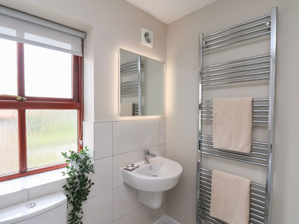 A bathroom with a sink, mirror, window, towel rack, and two towels at Buffers in Whitby