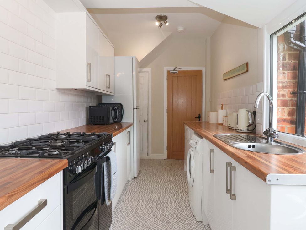 A kitchen with a gas stove, microwave, and sink at Sea View House in Hornsea
