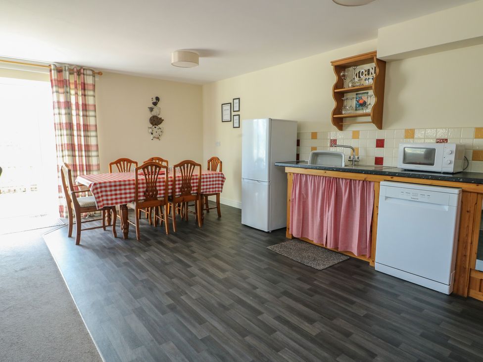 A kitchen with dining table and appliances at Ty Ni in Caeathro near Caernarfon