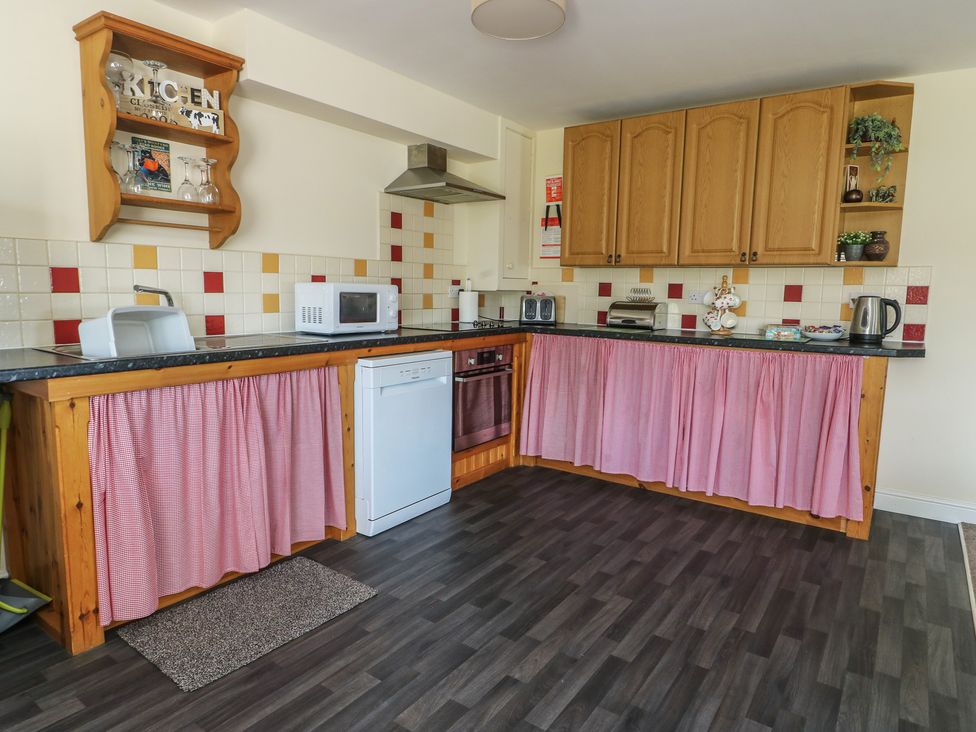 A kitchen with appliances and wooden cabinets at Ty Ni Caeathro near Caernarfon