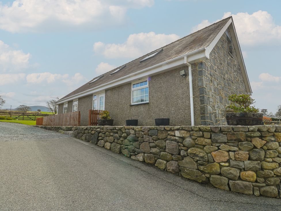 A house with a stone wall and plants at Ty Ni Caeathro near Caernarfon