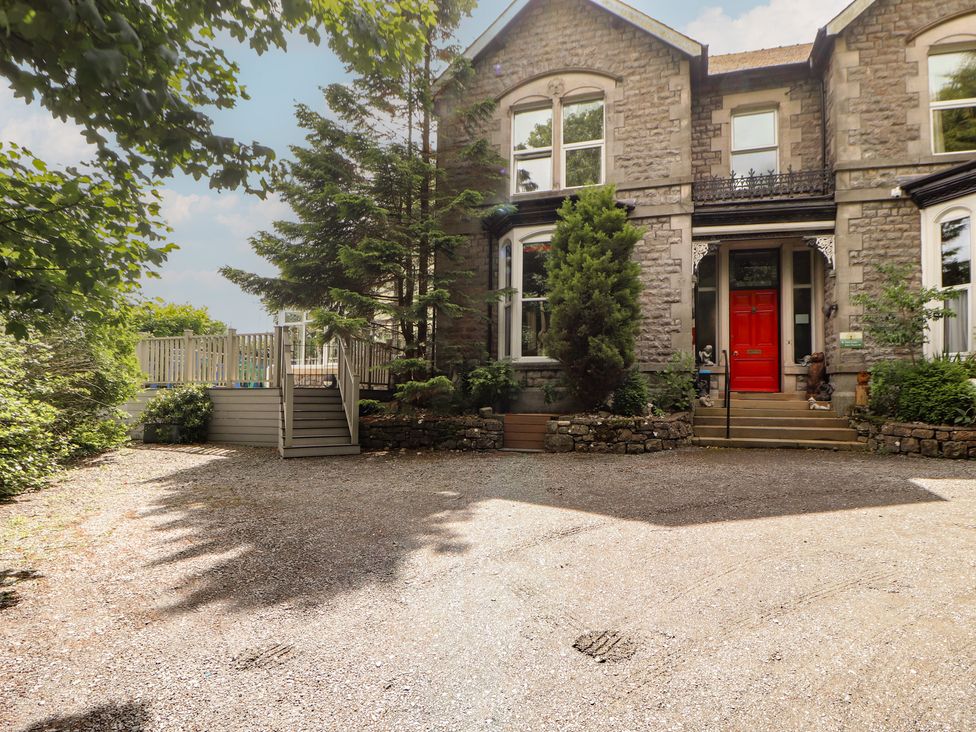 A stone building with a red front door and a gravel driveway at Eden Lodge in Bardsea