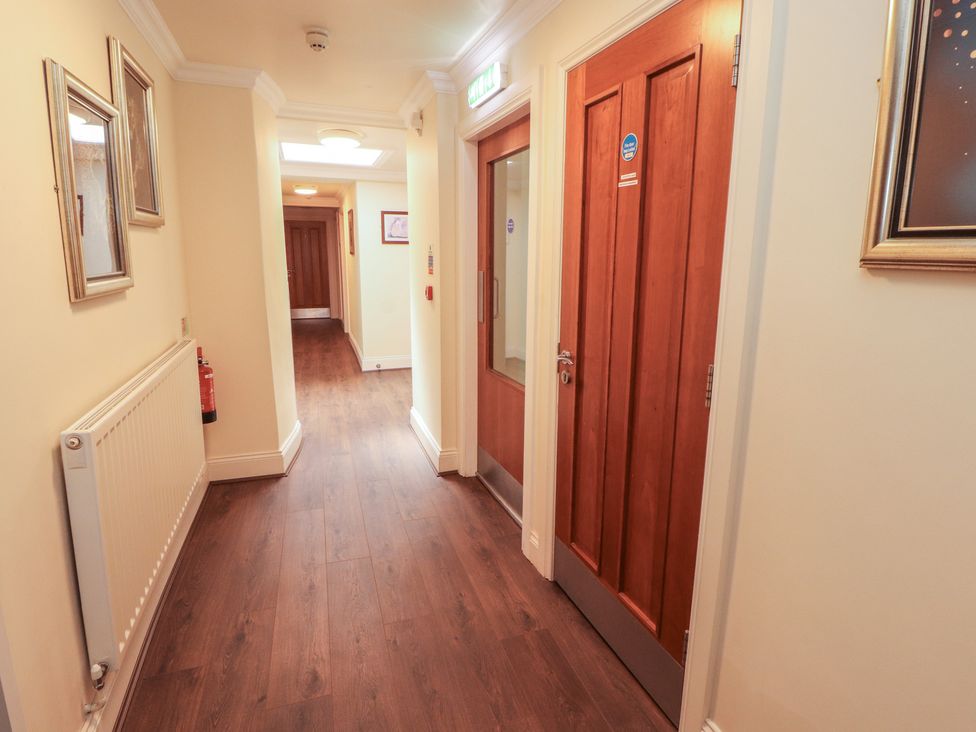 A corridor with wooden doors and wall frames at Eden Lodge in Bardsea