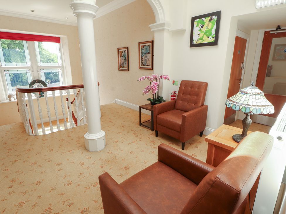 A hallway with an armchair and table at Eden Lodge in Bardsea